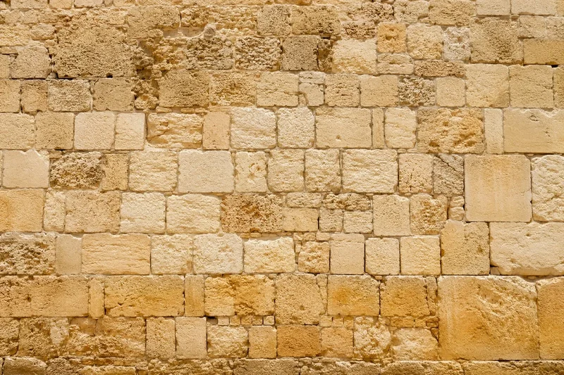 קיר אבן בטקסטורה משתנה עם גווני בז' וחום בהיר, מלבנים בגדלים שונים.