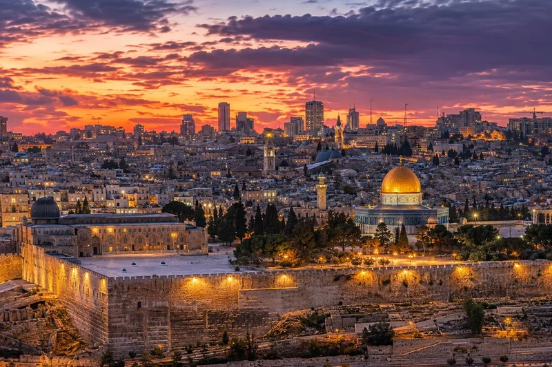 נוף עירוני בשעת שקיעה עם כיפה מוזהבת, שמיים סגולים וכתומים