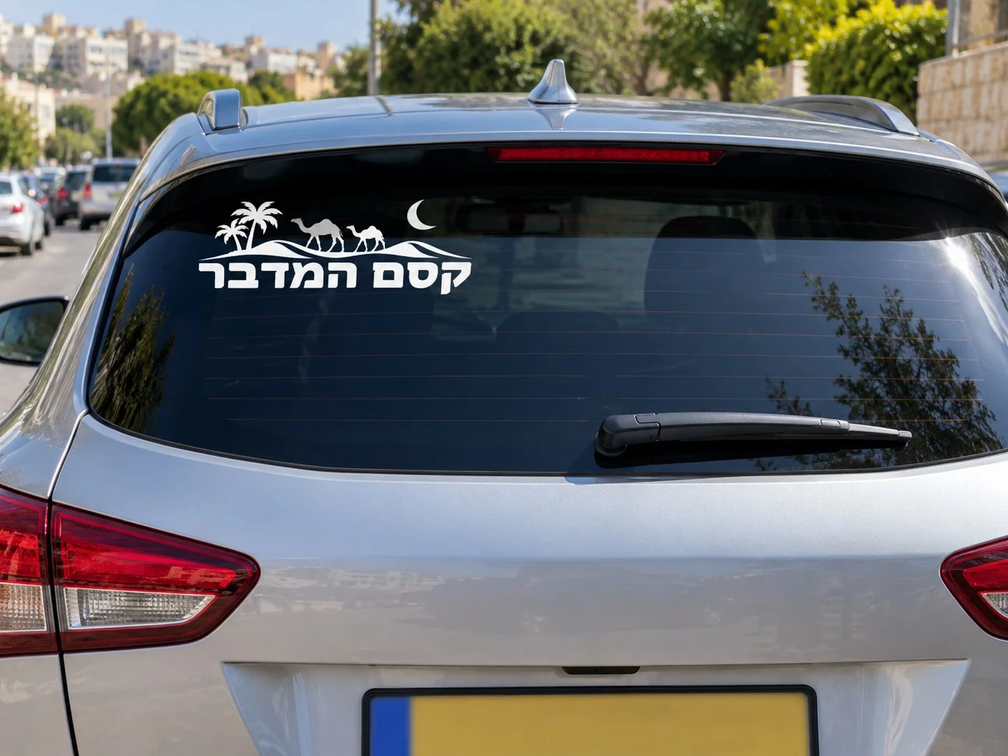 מדבקה עם גמלים ועצי דקל על השמשה האחורית של רכב שחור בעיר