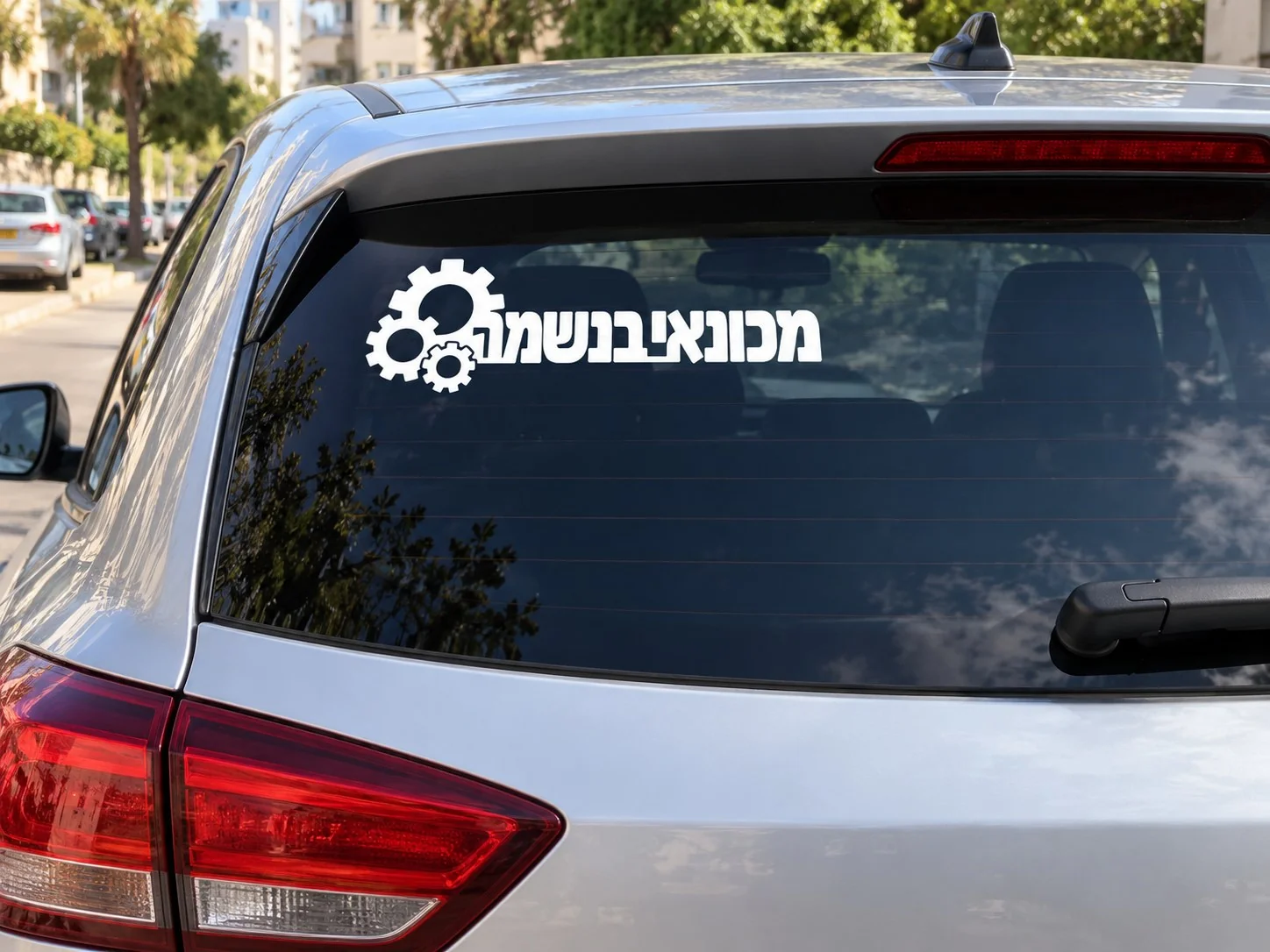 מדבקת 'מכונאי בנשמה' על שמשה אחורית של רכב אדום ברחוב עירוני.
