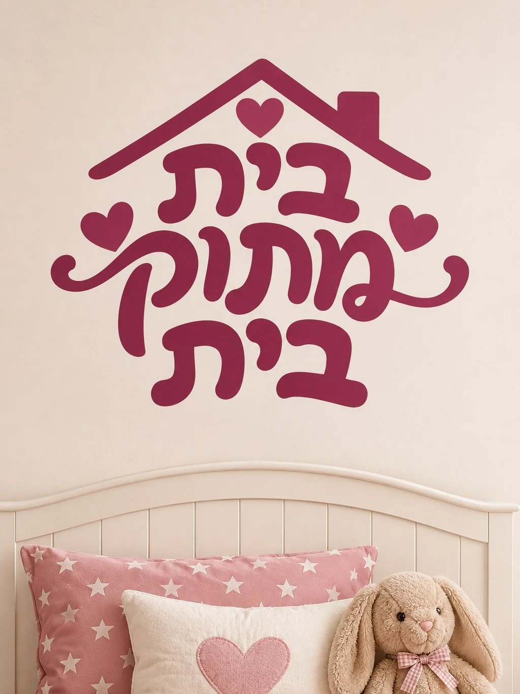 מדבקה עם טקסט עברי בעיצוב בית ולבבות על קיר בסלון מודרני עם כורסאות אפורות ושולחן זכוכית.